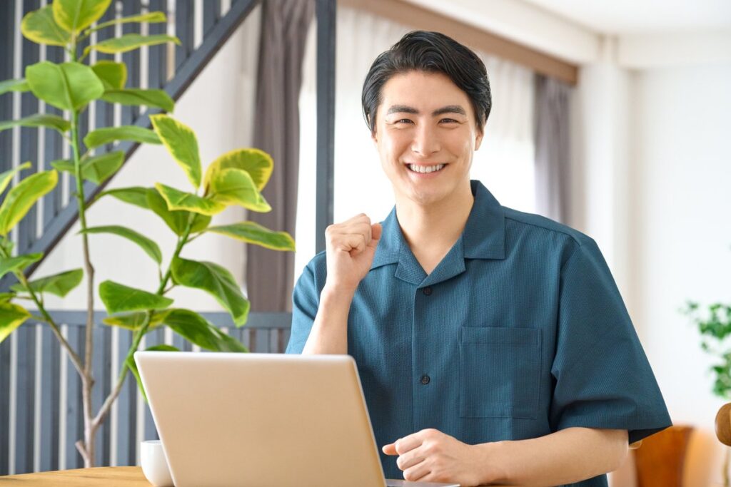 ノートパソコンの前で笑顔を見せるビジネスパーソン